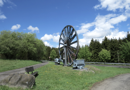 Das Grubenrad mit Lore markiert die Einfahrt zum 3 Stollen Besucherbergwerk Grube Bendisberg bei Langenfeld, © Touristik-Büro Vordereifel/ Svenja Schulze-Entrup Grubenrad Besucherbergwerk Grube Bendisberg