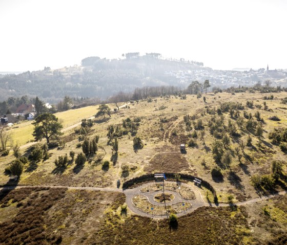 Blick auf eine hügelige Landschaft mit Bäumen und einem kleinen Labyrinth am Wanderweg Traumpfad Wacholderweg., © Eifel Tourismus GmbH, D. Ketz Blick auf eine hügelige Landschaft mit Bäumen und einem kleinen Labyrinth am Wanderweg Traumpfad Wacholderweg., © Eifel Tourismus GmbH, D. Ketz
