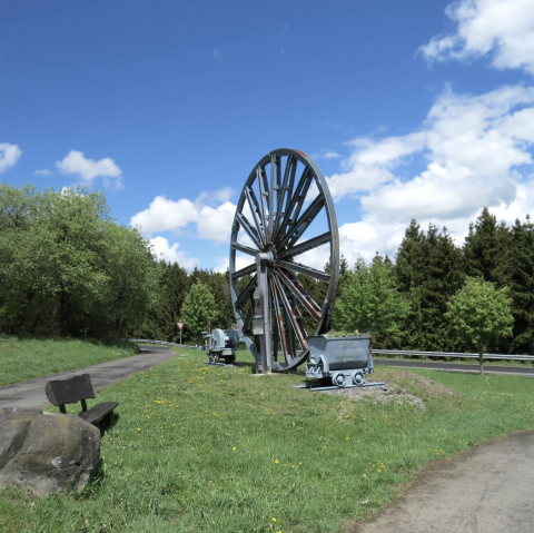 Das Grubenrad mit Lore markiert die Einfahrt zum 3 Stollen Besucherbergwerk Grube Bendisberg bei Langenfeld, © Touristik-Büro Vordereifel/ Svenja Schulze-Entrup Grubenrad Besucherbergwerk Grube Bendisberg