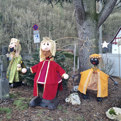 Drei Figuren der Heiligen Drei Könige in bunten Gewändern stehen vor einem Baum. Im Hintergrund sind ein Fachwerkhaus und ein Verkehrsschild zu sehen., © Svenja Schulze-Entrup Drei Figuren der Heiligen Drei Könige in bunten Gewändern stehen vor einem Baum. Im Hintergrund sind ein Fachwerkhaus und ein Verkehrsschild zu sehen., © Svenja Schulze-Entrup