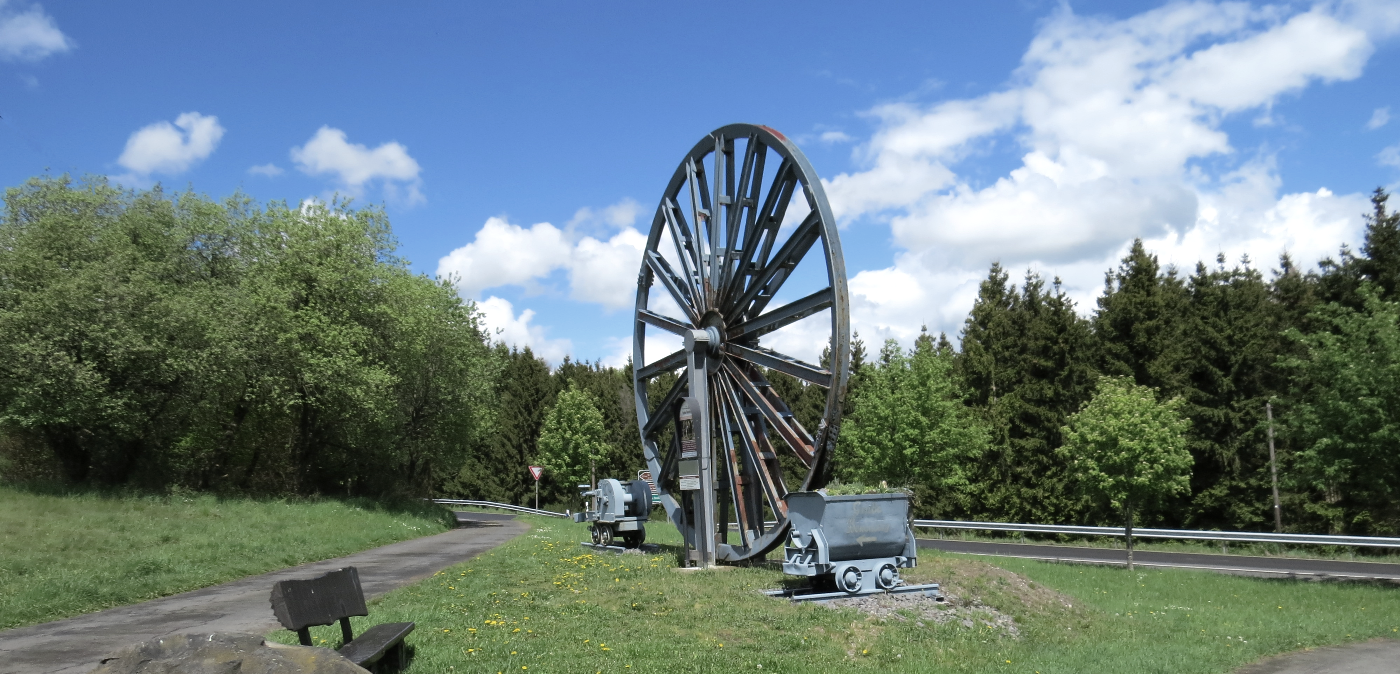 Das Grubenrad mit Lore markiert die Einfahrt zum 3 Stollen Besucherbergwerk Grube Bendisberg bei Langenfeld, © Touristik-Büro Vordereifel/ Svenja Schulze-Entrup Grubenrad Besucherbergwerk Grube Bendisberg