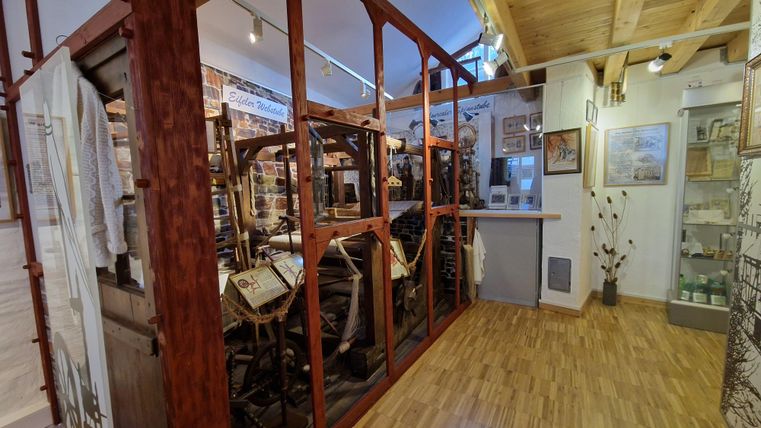 Eine Ausstellung in einem Museum mit historischen Maschinen und Geräten. Der Raum hat Holzboden und ist hell beleuchtet.