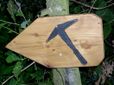 Wooden sign with a black slate hammer as a signpost in the forest.