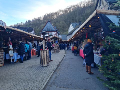 Ein Weihnachtsmarkt mit zahlreichen Ständen und vielen Besuchern. Die Atmosphäre ist festlich und einladend, umgeben von schönen alten Gebäuden.