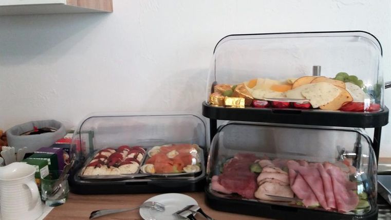 A breakfast buffet with various dishes. There are cold cuts, fruit, and pastries housed in two sales stands.