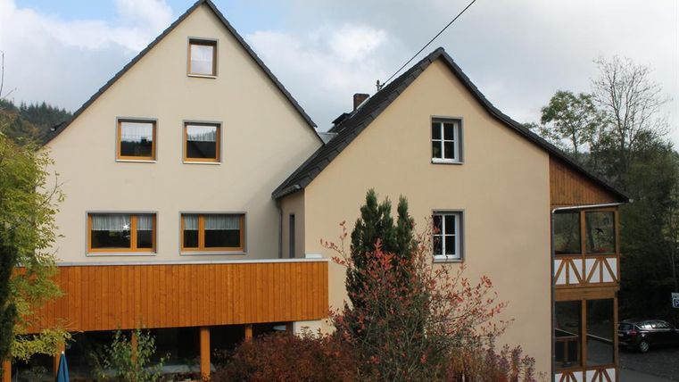 Ein modernes Haus mit einer Kombination aus Putz und Holz. Umgeben von Bäumen und einer schönen Landschaft.