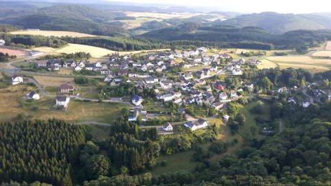 Eine ländliche Gemeinde mit vielen Häusern, umgeben von grünen Wäldern und Feldern. Die Umgebung ist hügelig und bietet eine ruhige, naturnahe Landschaft.