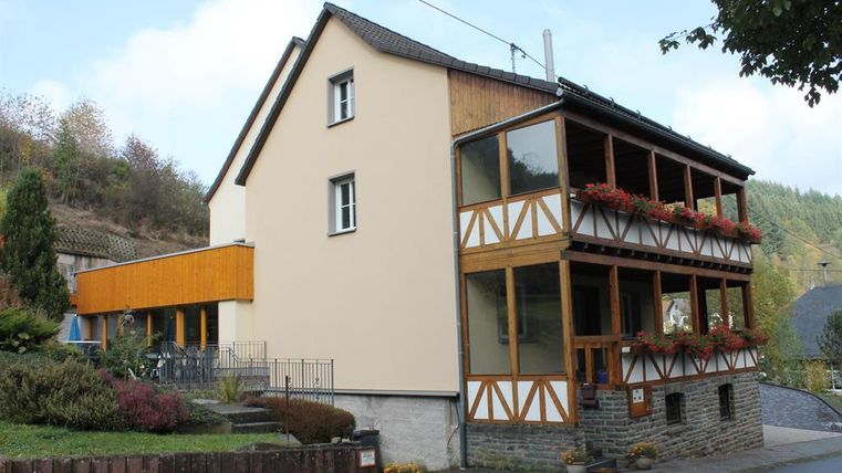 Ein charmantes Haus mit einer Kombination aus modernem und traditionellem Fachwerkstil. Der Eingang hat einen überdachten Bereich mit Blumen.