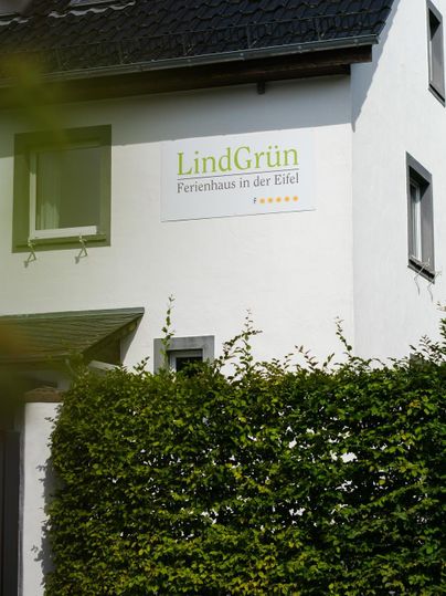A holiday home named "LindGrün" in the Eifel. The facade is bright and the windows are clearly visible.