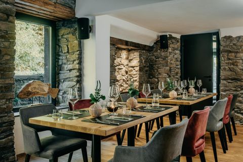 A modern restaurant with wooden tables and stylish chairs. Large windows allow plenty of light in and provide a view of the natural surroundings.
