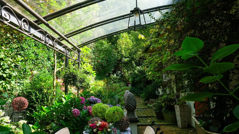 A beautiful garden with lush greenery and colorful flowers. A set table invites you to relax and linger.