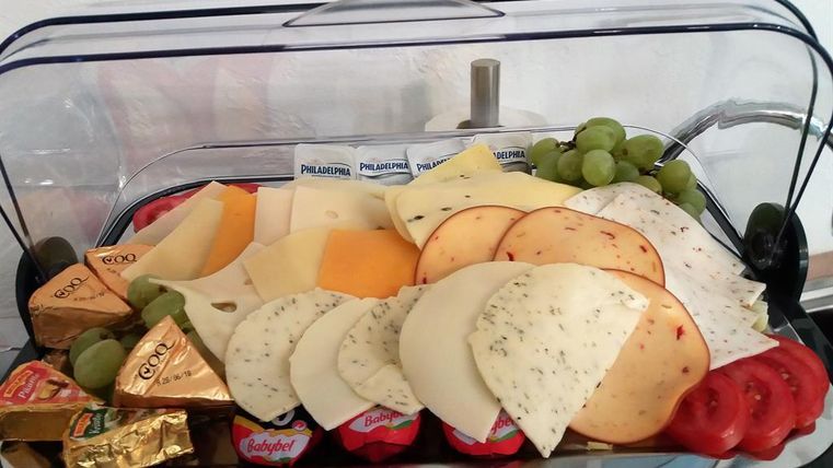 A selection of different types of cheese with grapes, tomatoes, and small portions of cheese. Served on a beautiful plate, it presents an appetizing platter for a snack or a party.