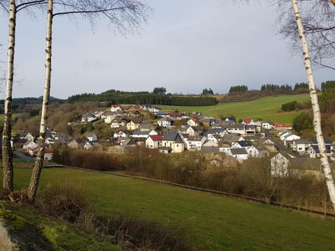 A picturesque rural landscape with a small village on a hill. Surrounded by meadows and trees, the scene exudes tranquility.