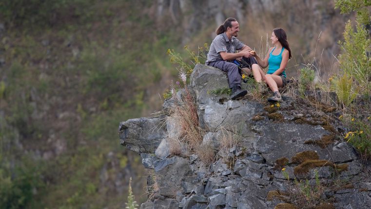Zwei Personen sitzen auf einem Felsen in einem Steinbruch und unterhalten sich.