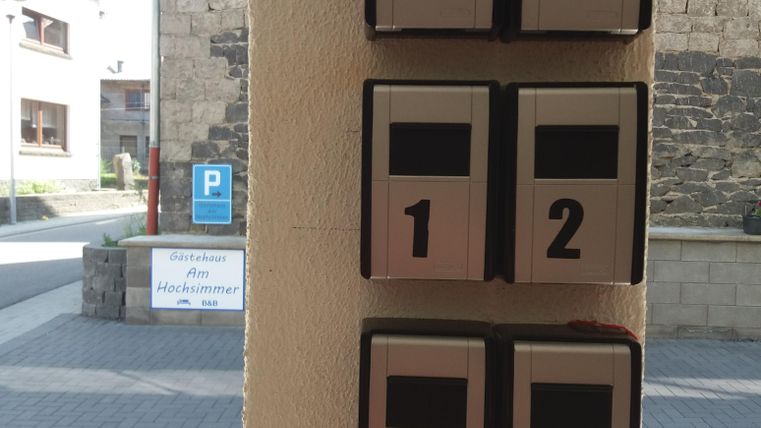 A mailbox with six compartments that are numbered. The compartments are made of metal and are mounted on a wall.