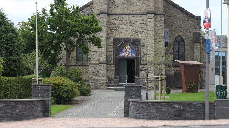 Eine traditionelle Kirche mit einem schönen Eingangsbereich. Umgeben von grünen Pflanzen und einem gepflegten Garten.