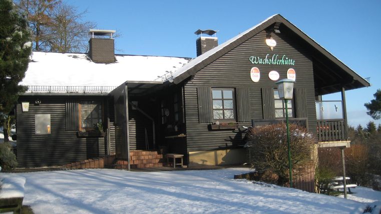 Ein schönes Holzhaus im Schnee. Der Himmel ist klar und blau, und die Umgebung ist winterlich.