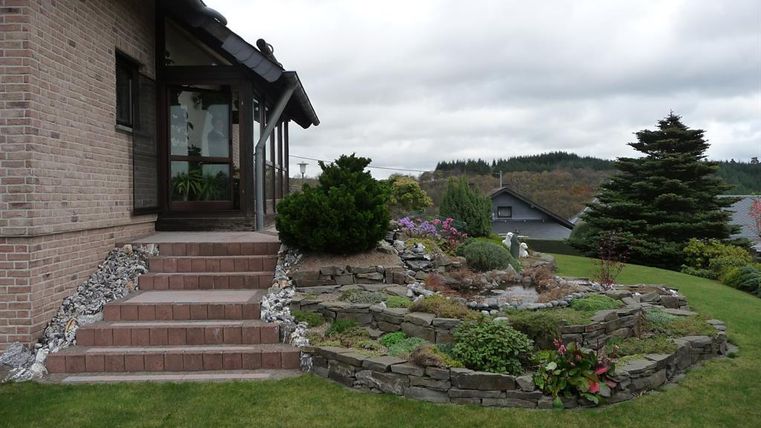 A house with a well-maintained garden landscape and a rock garden. The atmosphere is calm and inviting.