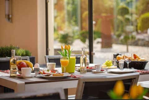 Ein schön gedeckter Tisch mit verschiedenen Speisen und Getränken. Im Hintergrund ist ein sonniger Garten zu sehen.