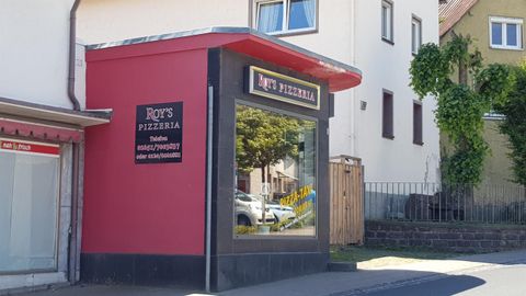 Ein Pizzarestaurant mit einem auffälligen roten und schwarzen Äußeren. Die große Fensterfront zeigt die Umgebung und lädt die Passanten ein.