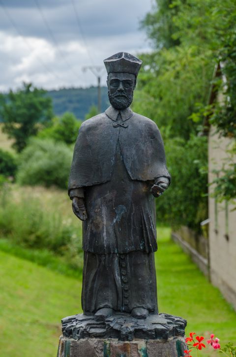 Bronze statue of a man in traditional dress on a pedestal outdoors.