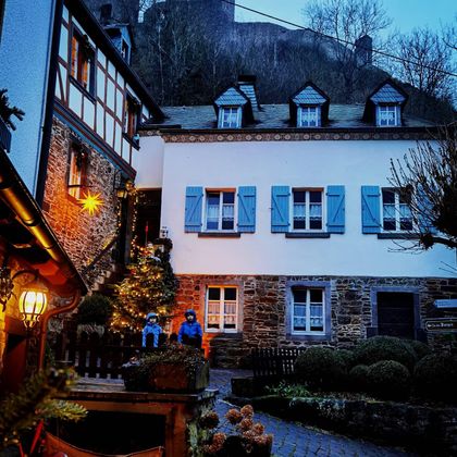 Ein malerisches Dorf mit charmanten Fachwerkhäusern und einem festlich geschmückten Weihnachtsbaum. Die Umgebung strahlt eine gemütliche Abendstimmung aus.