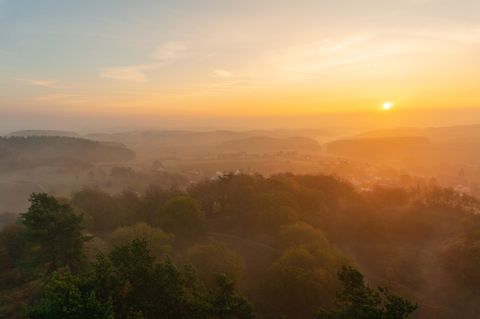 Sunrise over misty hills and wooded landscape