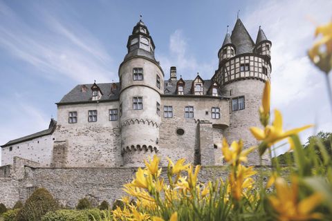 External view of Bürresheim Castle near Mayen. In the foreground, yellow flowers are blooming.