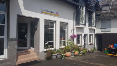 A modern building with large windows and an inviting entrance door. Flowering plants in pots stand in front of the building.