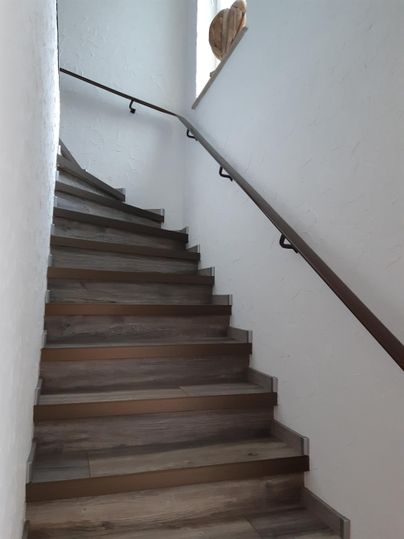 Eine Holztreppe windet sich nach oben. Die Wände sind schlicht und weiß gestrichen.