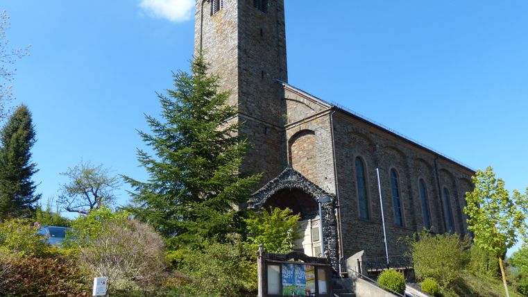 Exterior view of St. Bartholomew's Church with its stone tower and blue sky in the background.
