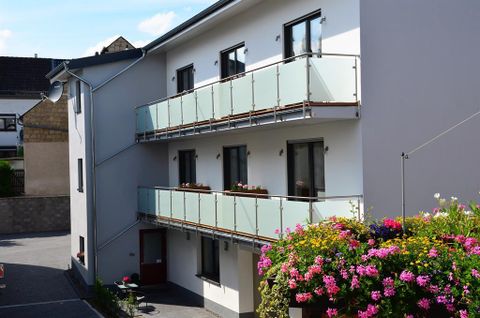 A modern building with balconies and colorful flowers. It is located in a quiet environment.