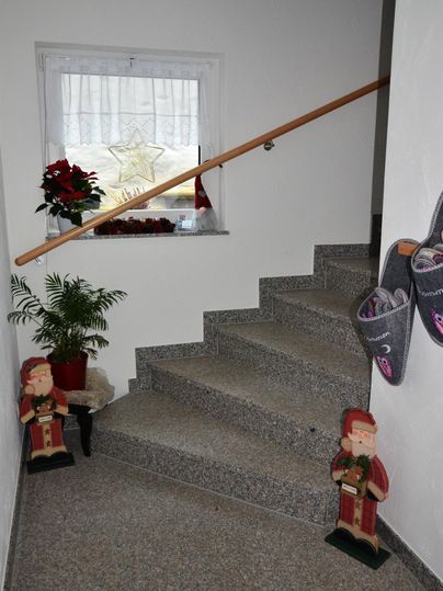 A staircase with gray steps and a handrail. Two decorative figures and a potted plant are on the stairs.