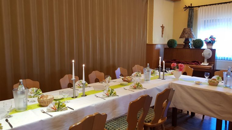 Ein festlich gedeckter Tisch mit Kerzen und dekorativen Elementen. Die Atmosphäre ist gemütlich und einladend.