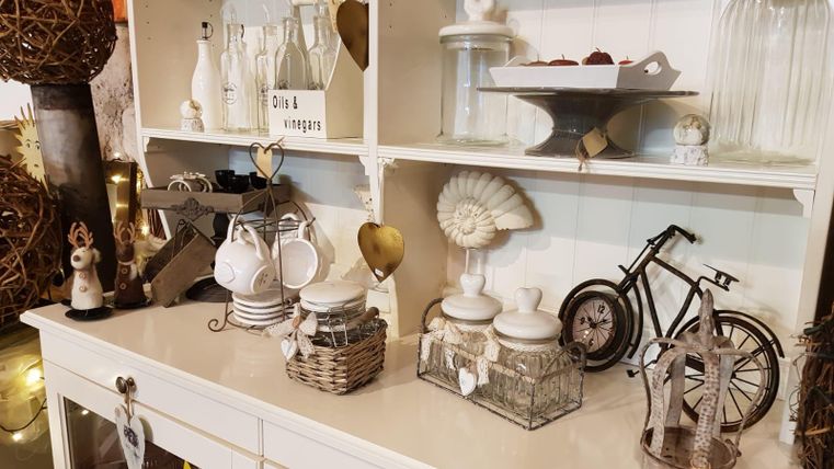 A beautiful setup with decorative objects like glass carafes, vintage crockery, and a small bicycle sculpture. Everything is arranged on a white sideboard, creating a cozy atmosphere.