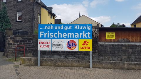 A sky-blue sign for a fresh market named Kluwig. It also displays logos of various local businesses.