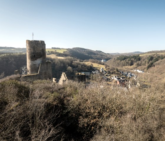Ruinen der Monrealer Burgen in h&uuml;geliger Landschaft, umgeben von B&auml;umen und einem Dorf im Tal. Blauer Himmel und klare Sicht., &copy; Eifel Tourismus GmbH, D. Ketz