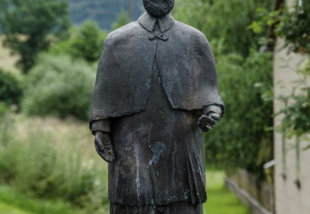 Bronzestatue eines Mannes in traditioneller Kleidung auf einem Sockel, umgeben von gr&uuml;ner Landschaft und bew&ouml;lktem Himmel., &copy; Volker Windheuser