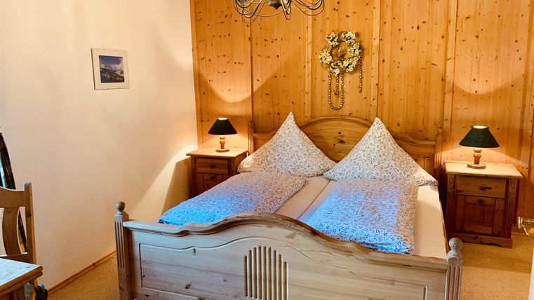 Ein einladendes Schlafzimmer mit Holzverkleidung und einem großen Bett. Zwei Nachttische und ein Kronleuchter sorgen für eine gemütliche Atmosphäre.