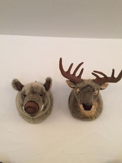 Two trophies of animals on the wall: a wild boar and a reindeer. Both are made of a soft, felt-like material.