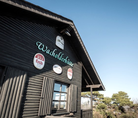 Die Wabelsberger Wacholderh&uuml;tte am Traumpfad Wacholderweg, mit Schildern an der Holzwand und klarem Himmel im Hintergrund., &copy; Eifel Tourismus GmbH, D. Ketz