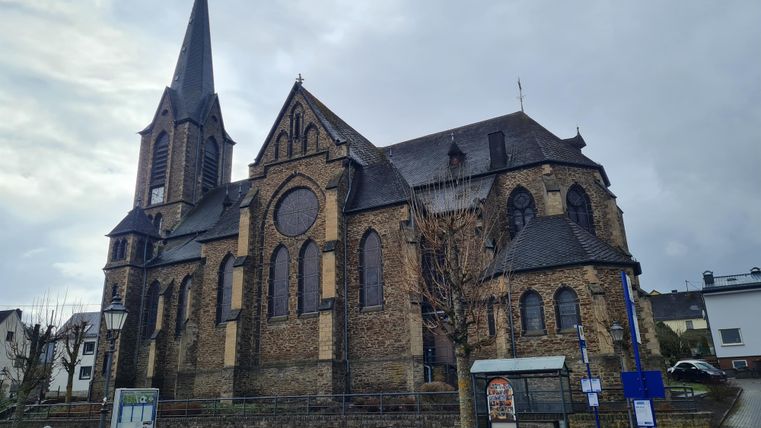 An impressive church with a tall tower and a historic façade. The sky is cloudy, which gives the scene a dramatic atmosphere.