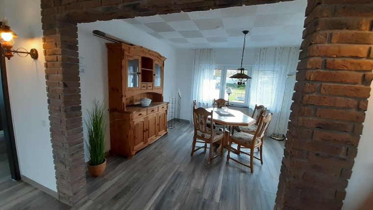 Ein gemütlicher Essbereich mit einem Holzschrank und einem großen Tisch. Der Raum hat helle Wände und viel natürliches Licht.