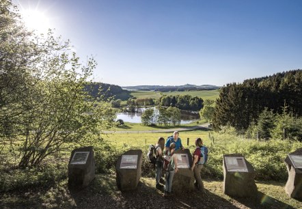 Wanderer betrachten Informationstafeln am Booser Doppelmaar. Im Hintergrund eine malerische Landschaft mit See und W&auml;ldern bei Sonnenschein., &copy; Kappest, REMET