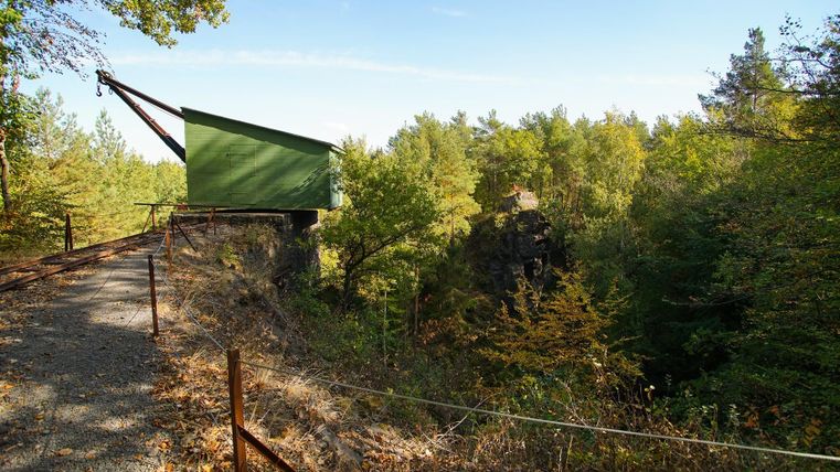 Eine grüne Aussichtsplattform in einem Waldgebiet. Umgeben von zahlreichen Bäumen und einer malerischen Landschaft.