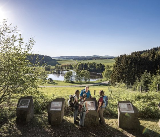 Wanderer betrachten Informationstafeln am Booser Doppelmaar. Im Hintergrund eine malerische Landschaft mit See und W&auml;ldern bei Sonnenschein., &copy; Kappest, REMET