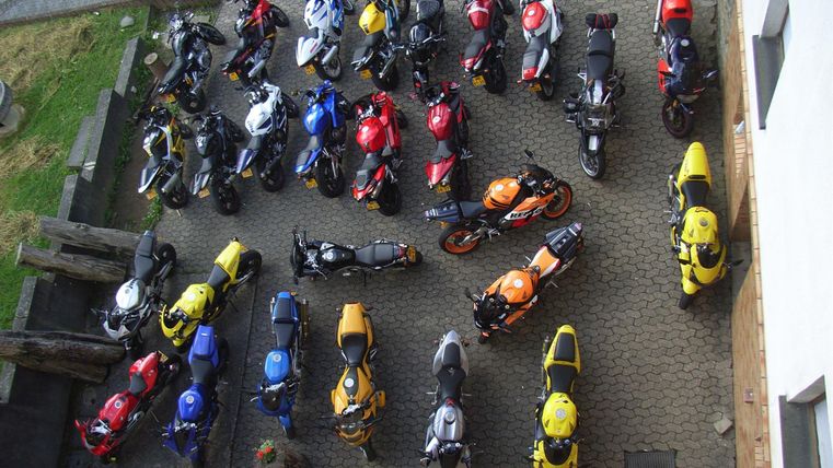 Eine Vielzahl von Motorrädern in verschiedenen Farben steht auf einem gepflasterten Platz. Die Anordnung der Motorräder ist geordnet und bietet einen bunten Anblick.