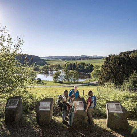 Wanderer betrachten Informationstafeln am Booser Doppelmaar. Im Hintergrund eine malerische Landschaft mit See und Wäldern bei Sonnenschein., © Kappest, REMET