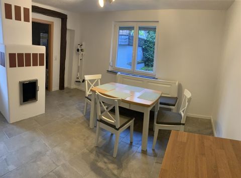 A modern dining area with a white table and chairs. The room has large windows that let in a lot of light.
