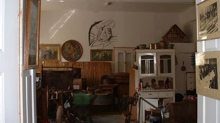 A cozy room filled with antique furniture and decorations. Pictures hang on the walls, and the room is furnished with various items.